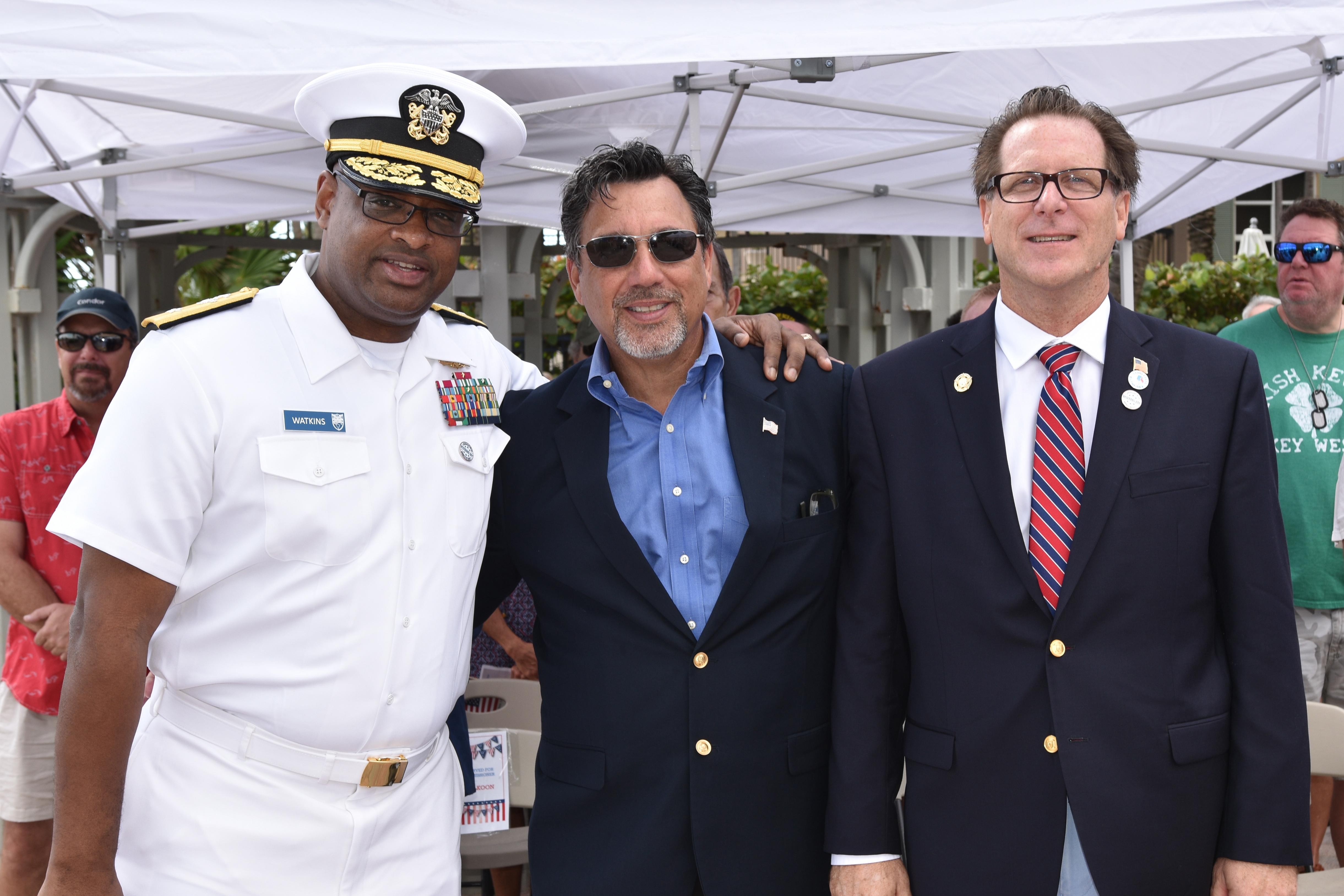 Randy Strauss posing with a U.S. Navy officer in front of military service flags